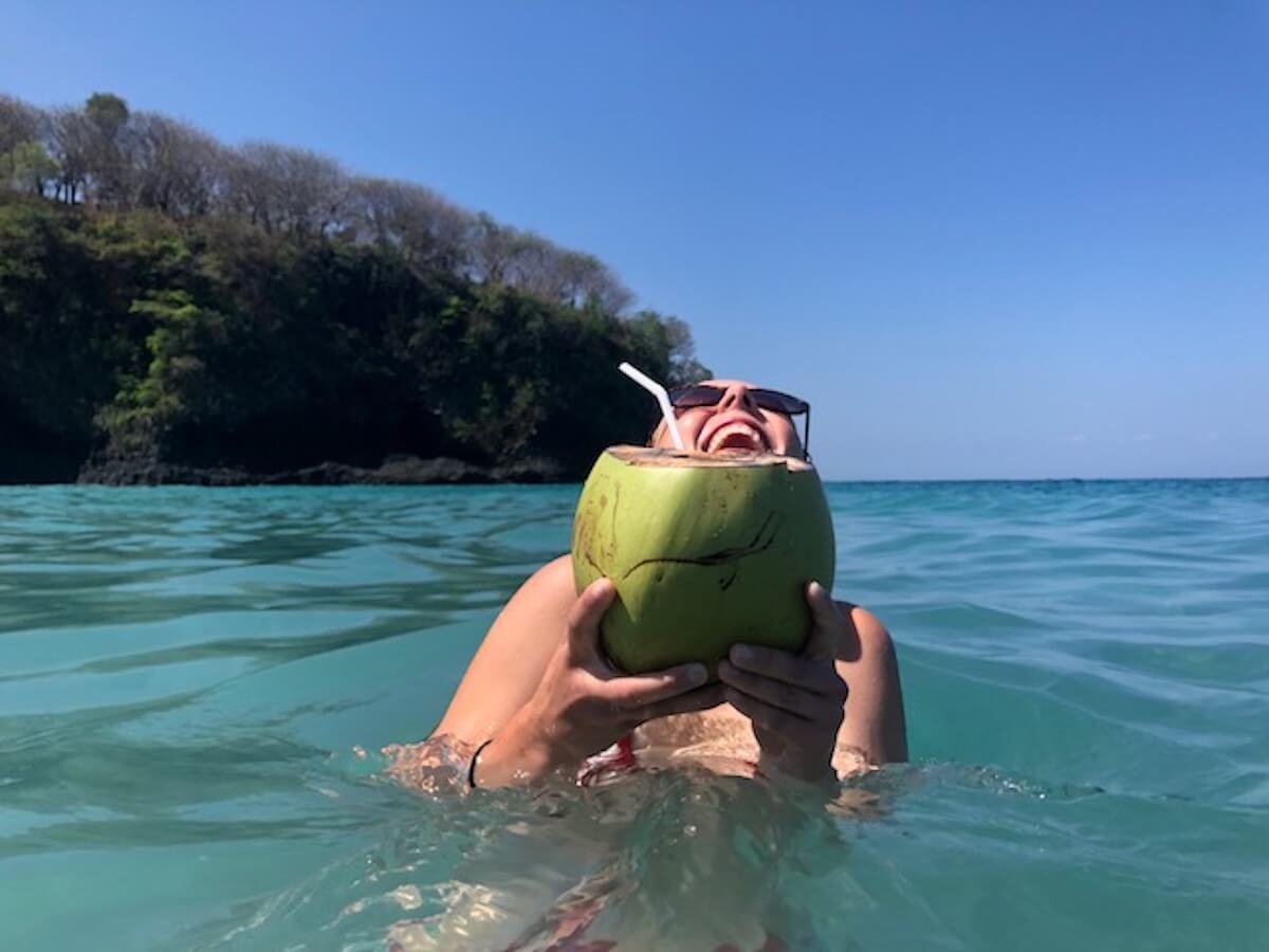 Kenza Coubrough holding an open coconut in the water