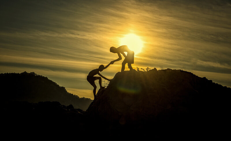 Two kids climbing hill in sunset