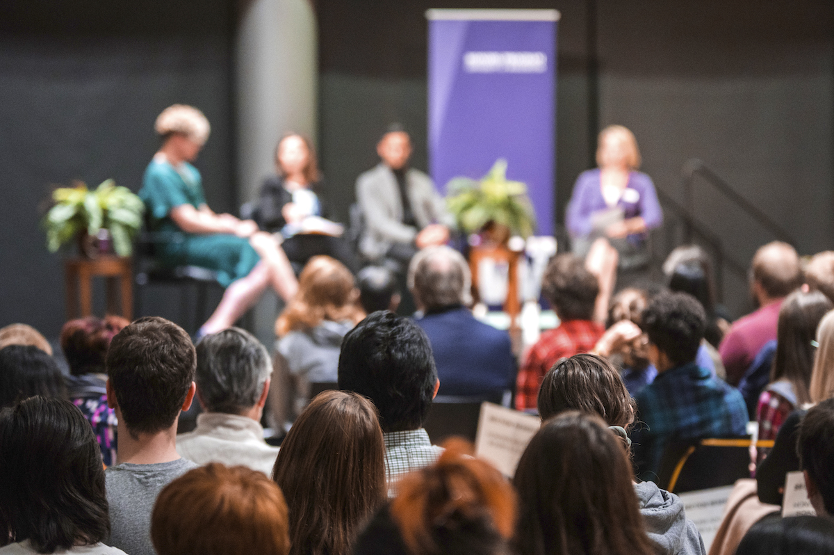 photo of speakers on the stage from amid the audience