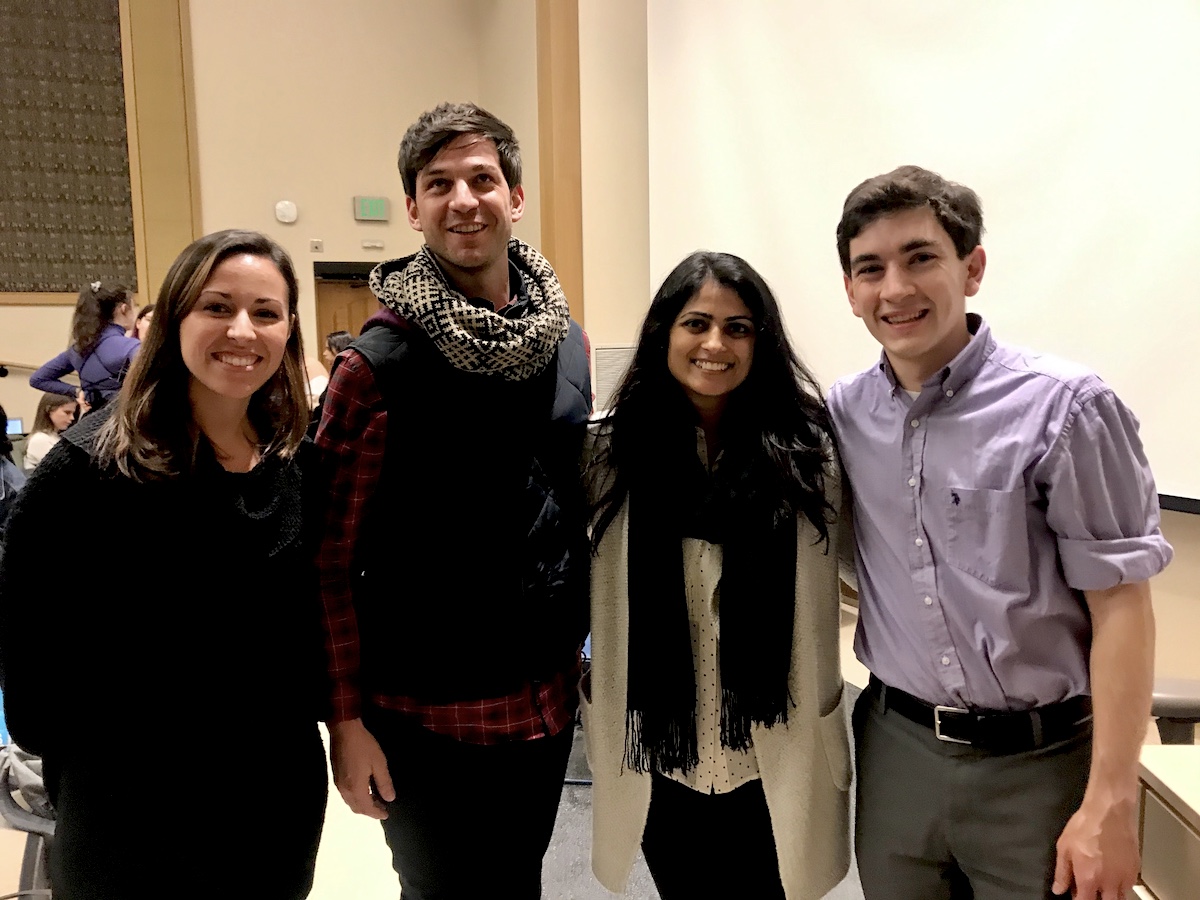 Alumni visitors to Honors 100 smiling together in a brightly lit classroom