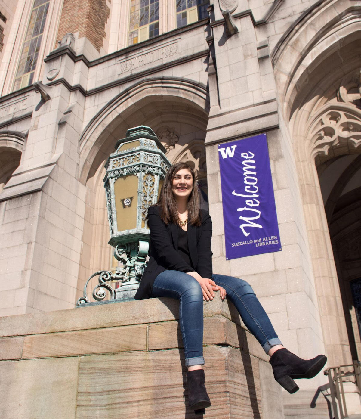 Reem Sabha sits on the steps of Suzzallo library on UW campus. She is smiling and it's a bright, sunny day.