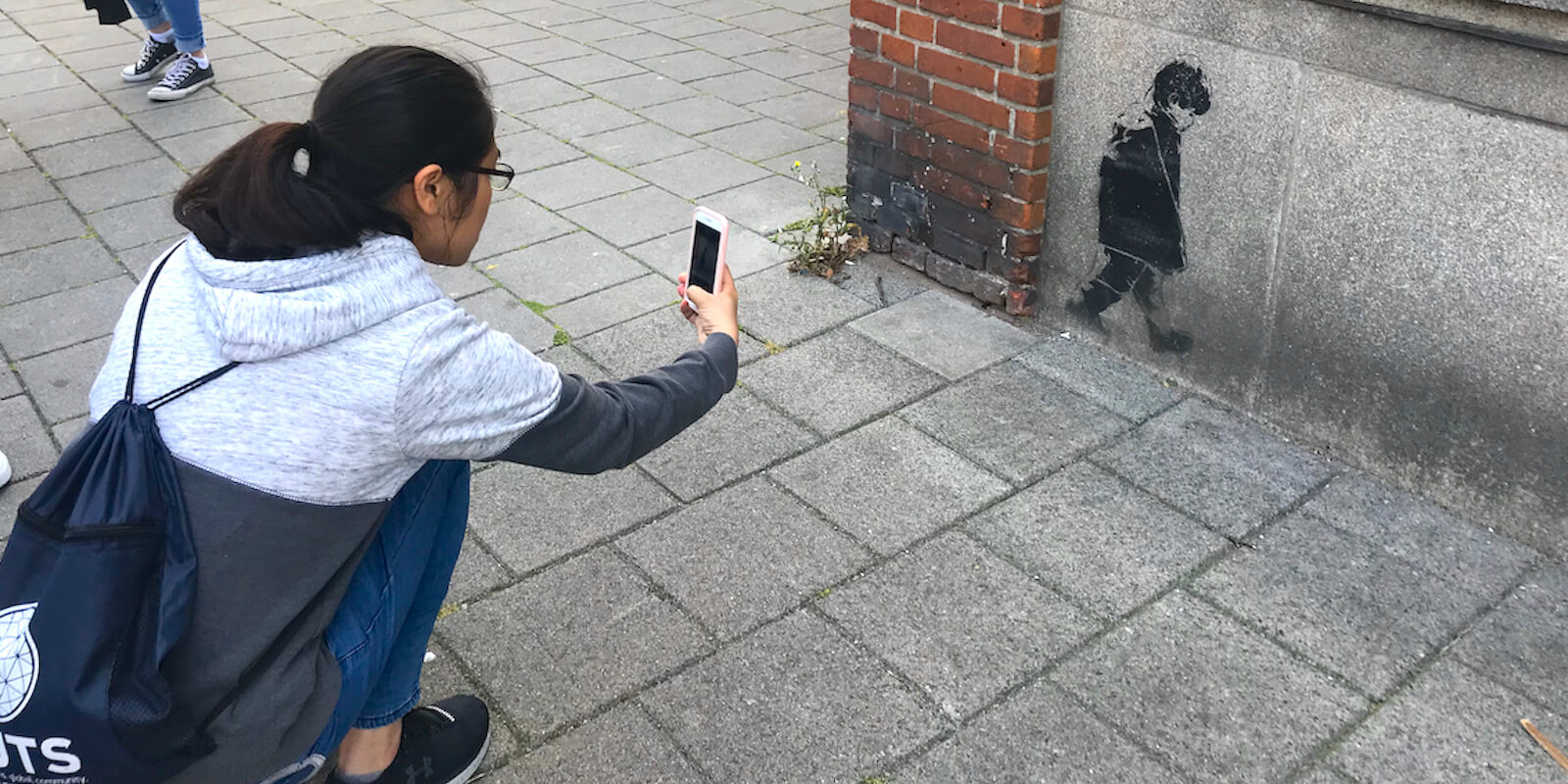 student noticing subtle street art - Amsterdam