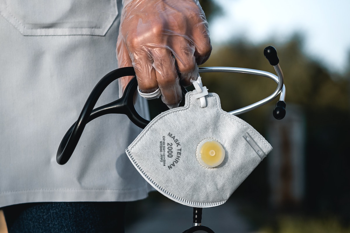 Anonymous doctor holds mask and stethoscope