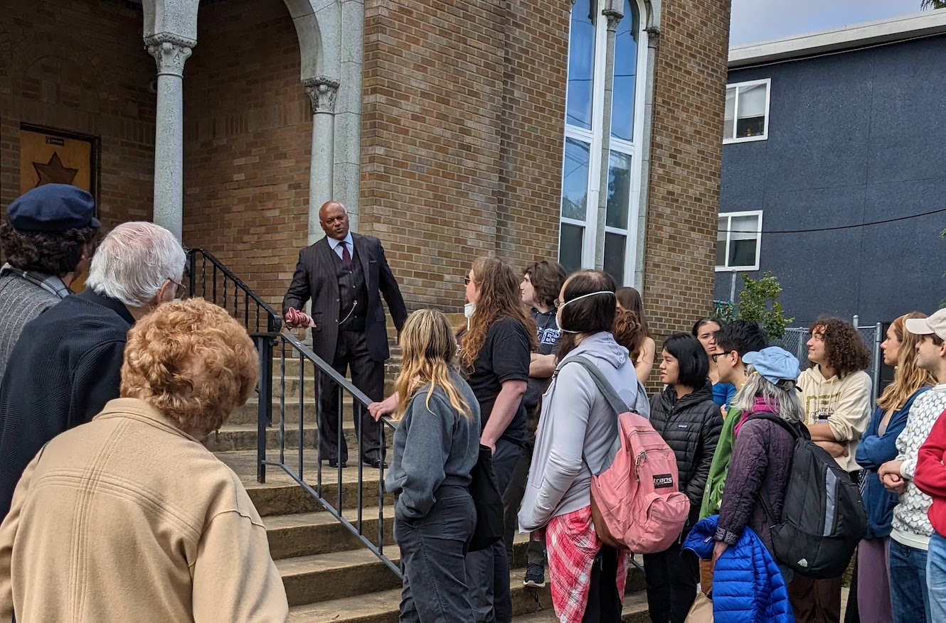 Photo of Pastor Kenny Isabell speaking with students and special guests on the steps of the Tolliver Temple.